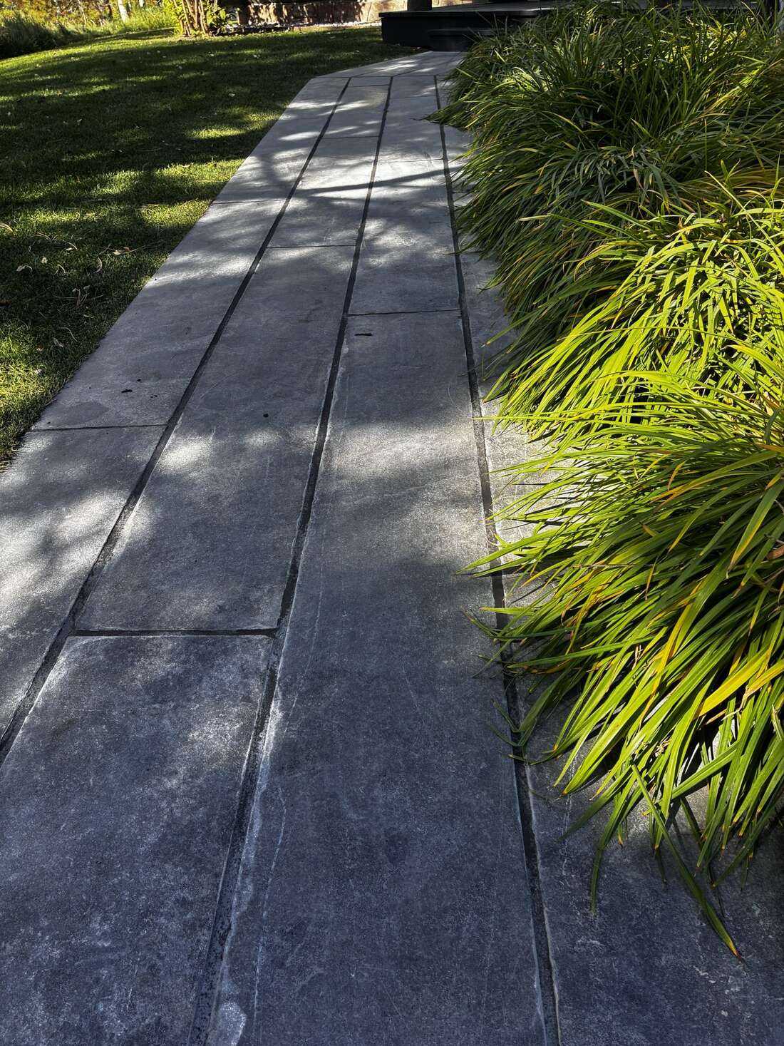 Bluestone walkway edged along a manicured lawn and planting bed