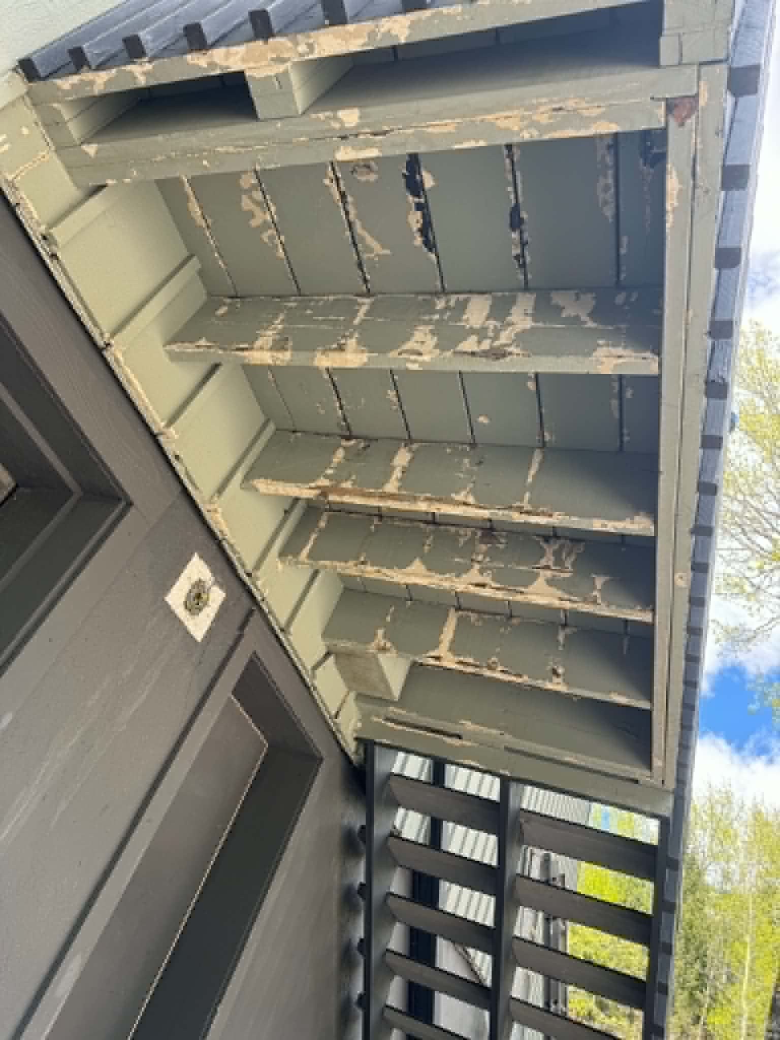 Peeling paint on porch ceiling soffit — before restoration