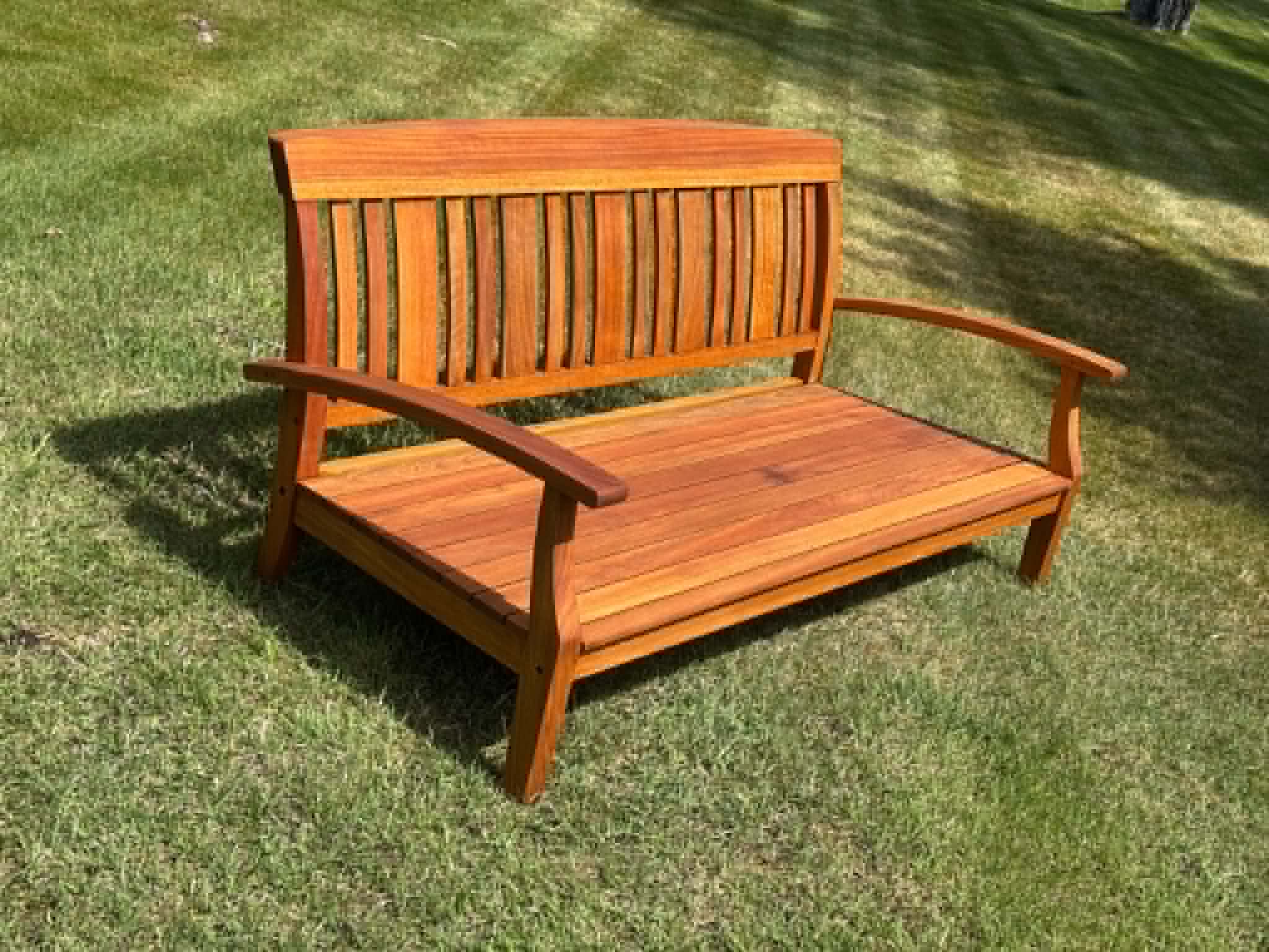 Freshly refinished teak garden bench on lawn